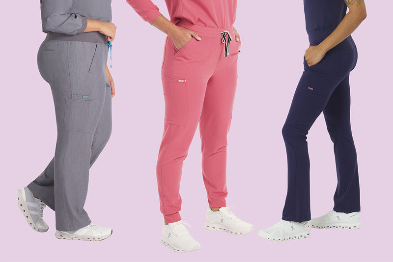 Three nurses wearing Dolan scrub pants in different styles and colors, designed for all-day comfort with supportive waistbands and breathable stretch fabric.