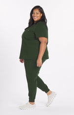 Woman wearing dark olive the Mayfair 2 pocket scrub top from DOLAN