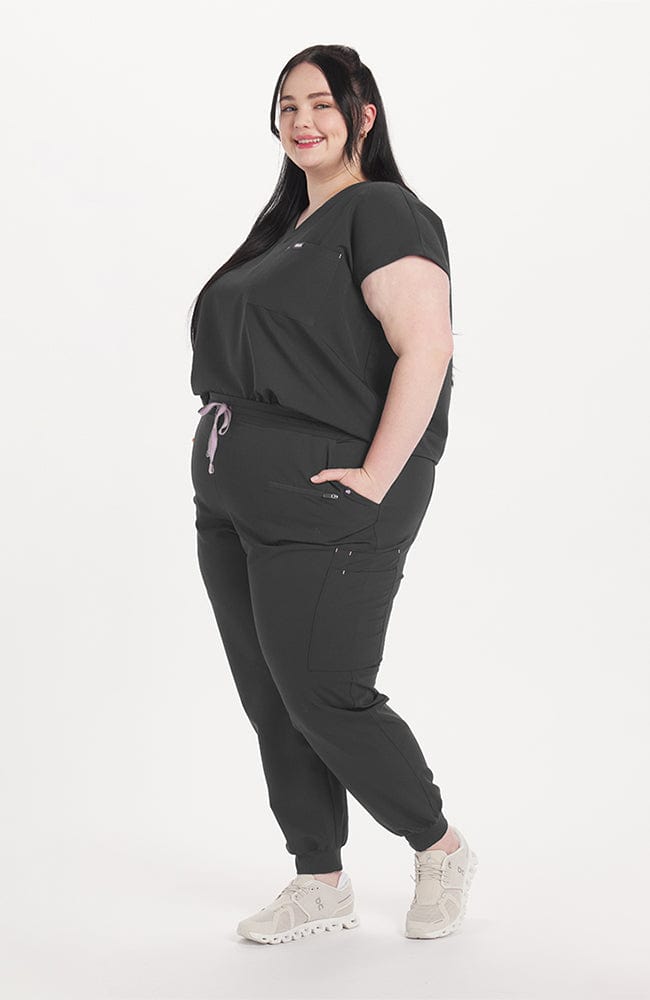 Woman in v neck scrub top with drop shoulder and 2 pockets in charcoal