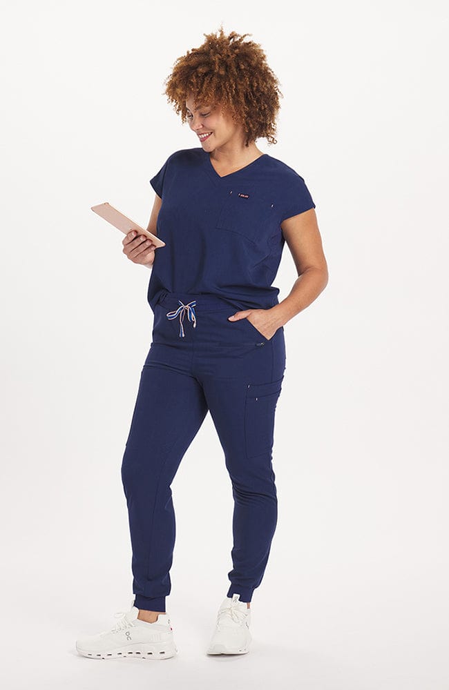 Woman in v neck scrub top with drop shoulder and 2 pockets in navy blue