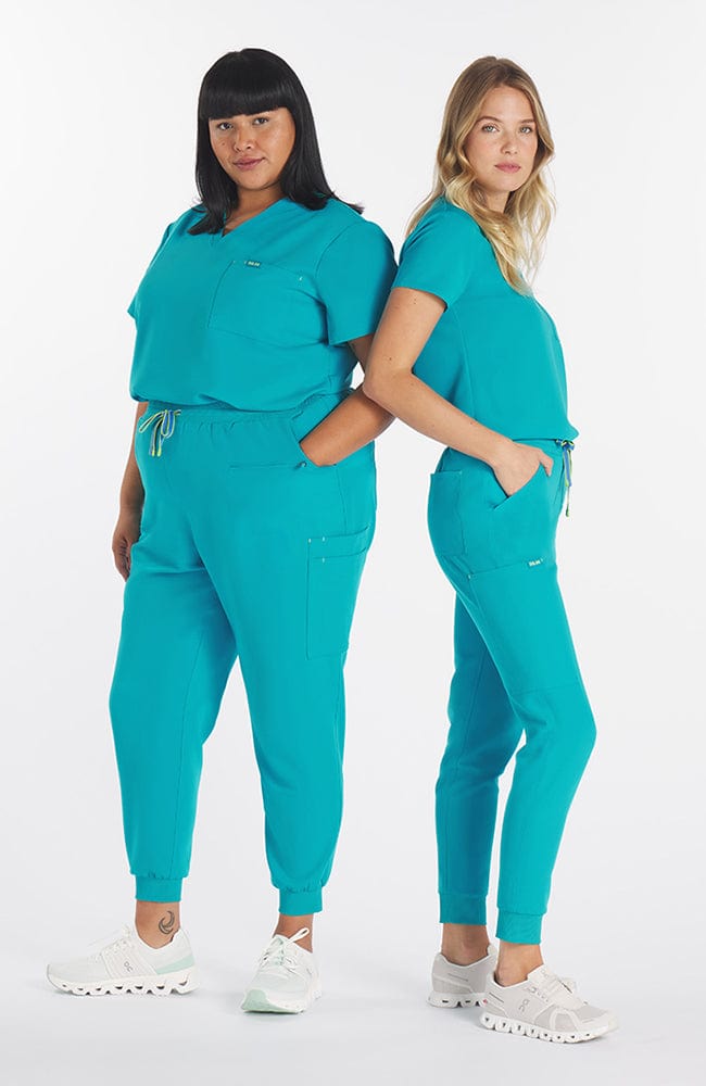 Super comfortable teal colored scrub pants with 11 pockets and V neck top on woman
