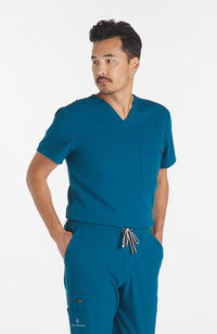 Man wearing Caribbean Blue Miguel V Neck 3-Pocket Men's CORE Scrub Top - DOLAN
