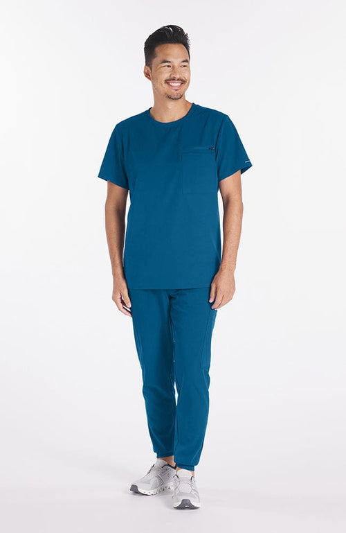 Man wearing Ravi Crew Neck 3-Pocket Men's CORE Scrub Top in Caribbean Blue