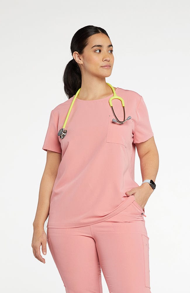 Woman wearing Chelsea Crew Neck 2-Pocket CORE Scrub Top in pink- DOLAN