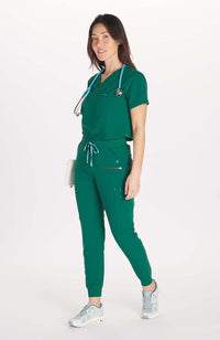 Woman in high waisted Hope 11 Pocket Jogger scrub pant in Hunter Green