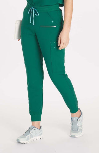 Woman in high waisted Hope 11 Pocket Jogger scrub pant in Hunter Green