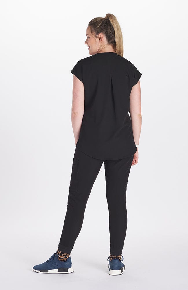 A pregnant woman wearing the DOLAN Pia Maternity Scrub Top 2-Pocket CORE and SOFIA Maternity Jogger Scrub 8-Pocket CORE in Black while putting her hand on her stomach. 